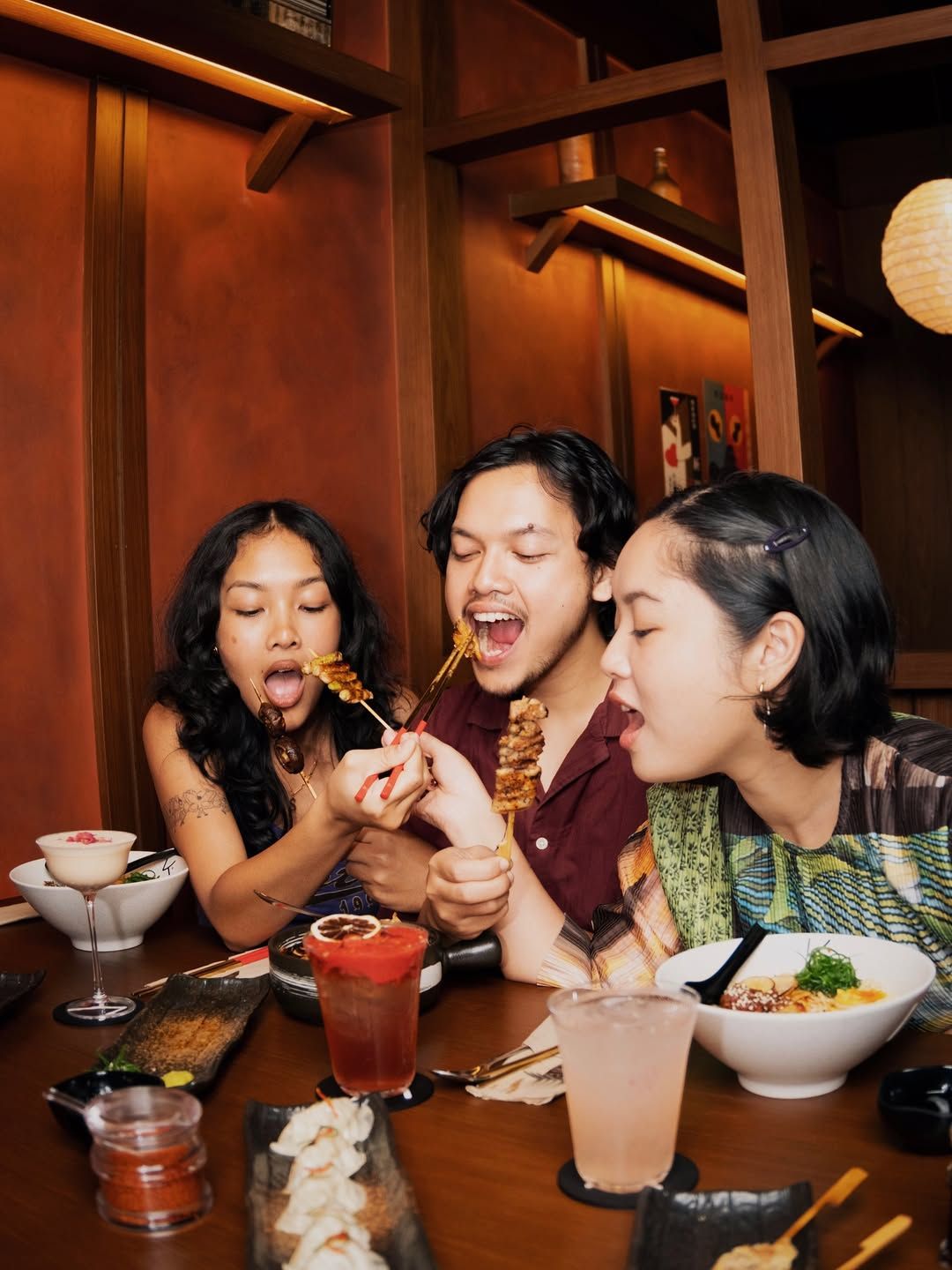 Three friends sharing satay